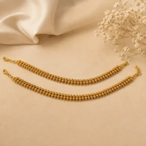 Gold-tone beaded double-layer jewelry chain displayed on a soft cream background with floral accents