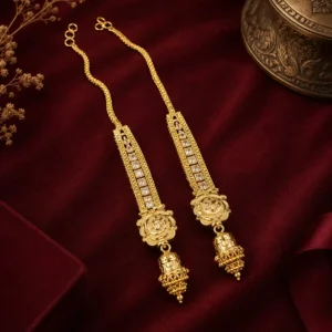 Traditional gold-tone long drop jewellery featuring intricate rectangular detailing, ornate floral motifs, and jhumka-inspired hanging pendants, displayed on rich burgundy velvet fabric.