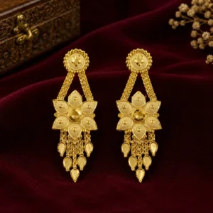 Gold-tone floral drop earrings with intricate petal detailing, hanging chain accents, and teardrop-shaped elements displayed against a burgundy velvet background.