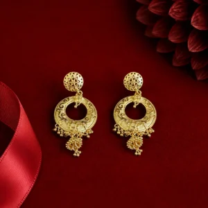 Pair of traditional gold-tone drop earrings with intricate floral filigree, circular engraved designs, beaded borders, and delicate dangling gold bead details displayed on rich red velvet.