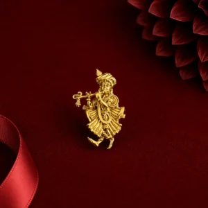 Gold-tone Krishna-inspired statement ring featuring a detailed flute-playing figure, displayed on rich red velvet with a red satin ribbon and softly blurred dark red floral accent.