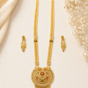 Elegant gold necklace set with matching traditional drop earrings arranged on a light ivory background, featuring an ornate floral pendant with red accents and intricate detailing.